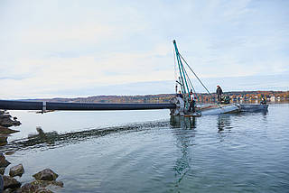 Arbeiter installieren auf einer schwimmenden Plattform die Rohrleitung am Starnberger See.